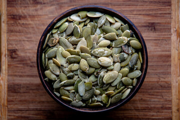 Peeled pumpkin seeds, in a ceramic bowl on a wooden table. Bakery ingredients. Products for tasty and healthy food.