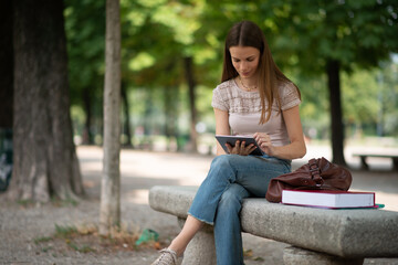 Girl with tablet sitting on a park bench