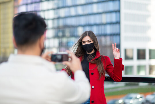Man photographing girlfriend making victory sign during covid or coronavirus pandemic