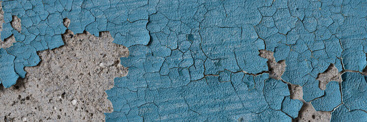 Peeling paint on the wall. Panorama of a concrete wall with old cracked flaking paint. Weathered rough painted surface with patterns of cracks and peeling. Wide panoramic texture for grunge background
