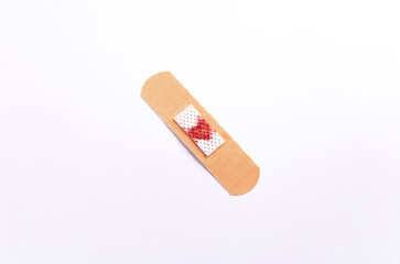 Medical band-aid with a red heart on it, on a white background. Flat lay.