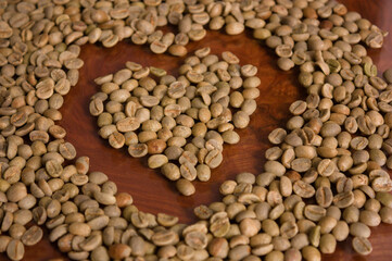 A heart formed in the center of a pile of unroasted coffee beans