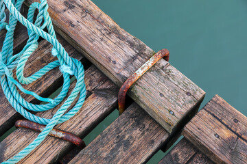 Naklejka premium Wooden pier with blue sea. Wood floor or terrace beside the blue crystal clear water and a rope.