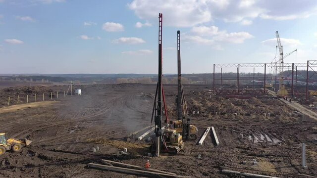 Excavation at a construction site, diesel pile driving machine with rumble and smoke drives piles deep into the ground to ensure the strength of the foundation of the future structure