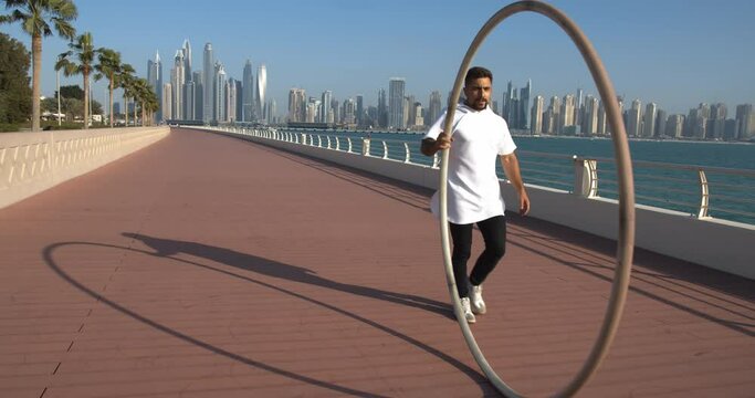 Sportsman is walking and rolling the hoop on Palm Jumeirah in Dubai, gymnast, 4k