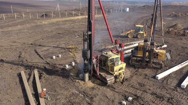 Excavation at a construction site, diesel pile driving machine with rumble and smoke drives piles deep into the ground to ensure the strength of the foundation of the future structure