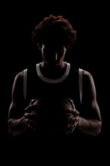 Fototapeta na wymiar Professional basketball player holding a ball against black background. Serious concentrated african american man in sports uniform