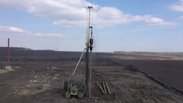 Excavation at a construction site, diesel pile driving machine with rumble and smoke drives piles deep into the ground to ensure the strength of the foundation of the future structure