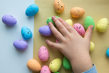 Child's hands are touching colorful Easter eggs. The child is playing with Easter eggs. Happy easter.