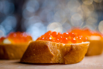 baguettes with red caviar very close close-up on a wooden tray with herbs and a light bright...
