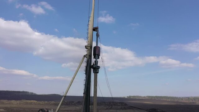 Excavation at a construction site, diesel pile driving machine with rumble and smoke drives piles deep into the ground to ensure the strength of the foundation of the future structure