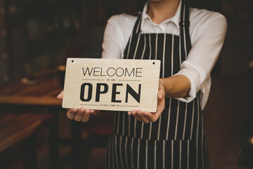 Female receptionist holding a store opening sign with customer service in a food and beverage restaurant