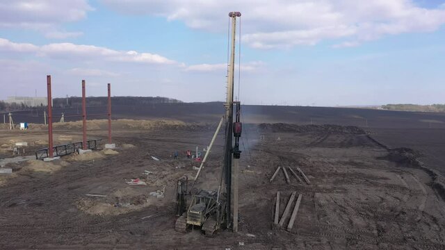 Excavation at a construction site, diesel pile driving machine with rumble and smoke drives piles deep into the ground to ensure the strength of the foundation of the future structure
