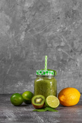 Freshly made kiwi lime and spinach smoothie on a gray concrete background.