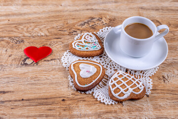 Homemade heart-shaped cookies, with white icing and sprinkles with coffee