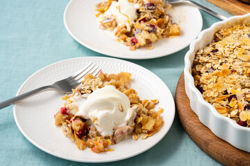 Apple and pear crumble with ice cream, streusel. Fruit topped crisp oat crumbly mixture served ice cream. Apple cobbler pie with nuts. Side view. Two plate with gluten free low calories diet dessert.