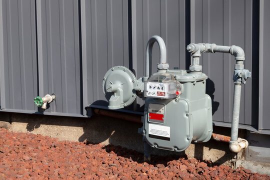 An angular view of a residential gas meter and pressure regulator mounted on the exterior of the home