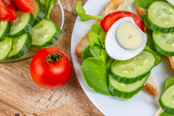 Fried bread toasts with vegetable and egg slices and salad