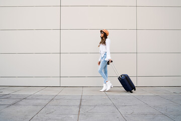 Young woman carrying a suitcase outdoors.