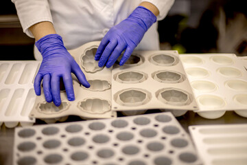 Portrait of adorable female chef in uniform holding heap of rubber mold tray for cooking pastry