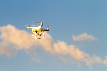 Drone flying in blue sky with clouds in the background