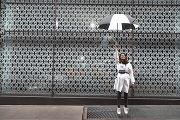 Fashion woman portrait holding umbrella against patterned wall background. White and black color...