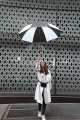 Fashion woman portrait holding umbrella against patterned wall background. White and black color theme conceptual photo. Geometric shapes, unique creative ways 