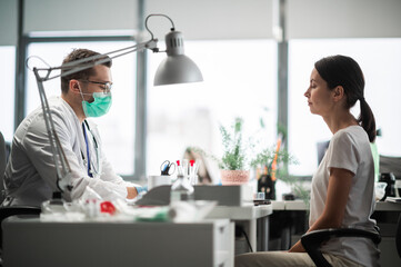 Fototapeta premium A young doctor is receiving a female patient at a desk in his office