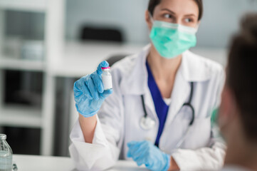 A young medical woman holds a bottle of vaccine in her hands and shows it