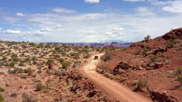 Aerial view of offroad vehicle driving through red rock canyons