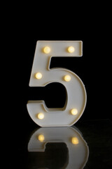 Number 5 (five), in a plastic part, with round flashing lights, with black background on a reflective surface