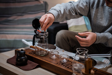 Fototapeta na wymiar The process of tea ceremony at home. The tea master puts pieces of raw aged black tea in a teapot on a bamboo tray.