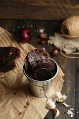 Homemade beef jerky seasoned with garlic, onion, pepper and salt. Jerky in a bucket on a wooden...
