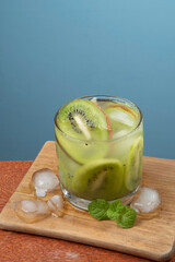 alcoholic drink caipirinha based on kiwi and aguardente distilled cocktail drink and fruits on blue background