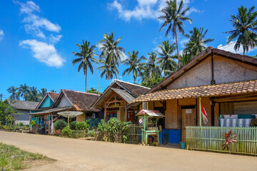 Fototapeta premium Traditional house of beachside village with coconut trees under blue skies. Daylight in the Countryside of Asia. 