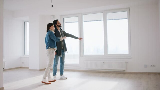 Young couple owners visualising design of new flat, new home and relocation concept.