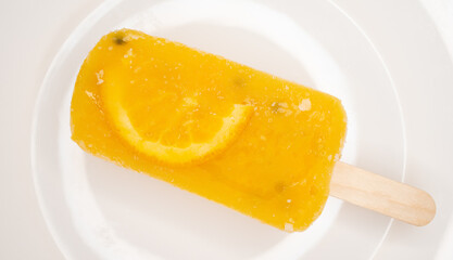 fresh passion fruit flavor popsicle with slice of orange on a dish