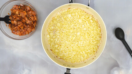 Fried chopped onion on frying pan, close up view from above. Sour cream chicken paprika recipe, step by step cooking process