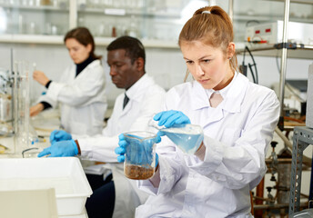 Fototapeta premium Serious woman lab scientist in glasses working with reagents and test tubes in laboratory