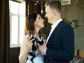 Young newlywed couple drinking wine and smiling at their happiness, romance and tenderness