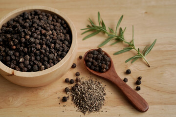 Black pepper in a cup with wood grain background, industry concept