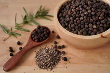 Black pepper in a cup with wood grain background, industry concept