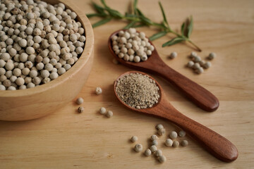 White pepper in a cup with wood grain background, industry concept