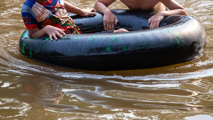 Close up Black rubber ring with children playing in the river. A family holiday activity during the hot weather of Thailand. Children are happy and relaxed. Rubber ring in the river