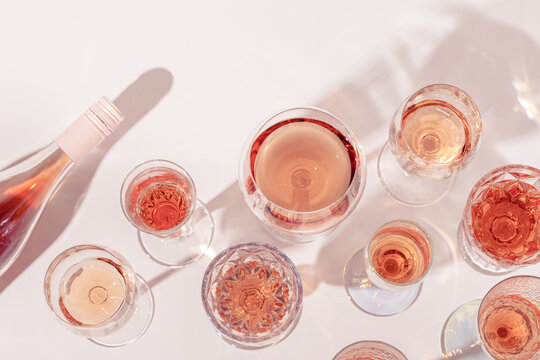 Many Glasses Of Rose Wine And Bottle Sparkling Pink Wine Top View. Light Alcohol Drink For Party.