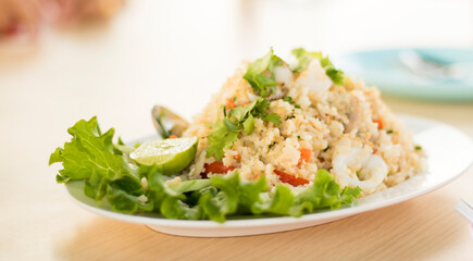 Fried rice with vegetables and vegetables arranged in a plate on a restaurant table.