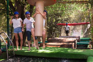 Fototapeta na wymiar Friends help each other overcome water obstacles in theme park. High quality photo