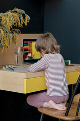 Distance education at home, online class. Boy in pajamas learns to draw during an online lesson