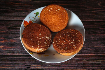 Foto de cupcakes recién horneados y listos para comer en una vasija de porcelana con un vaso de leche al fondo. 