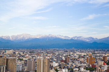 Obraz premium Toyama cityscape and Tetayama mountain range (Japan alps) views from Kasui park in Toyama city, Toyama, Japan.